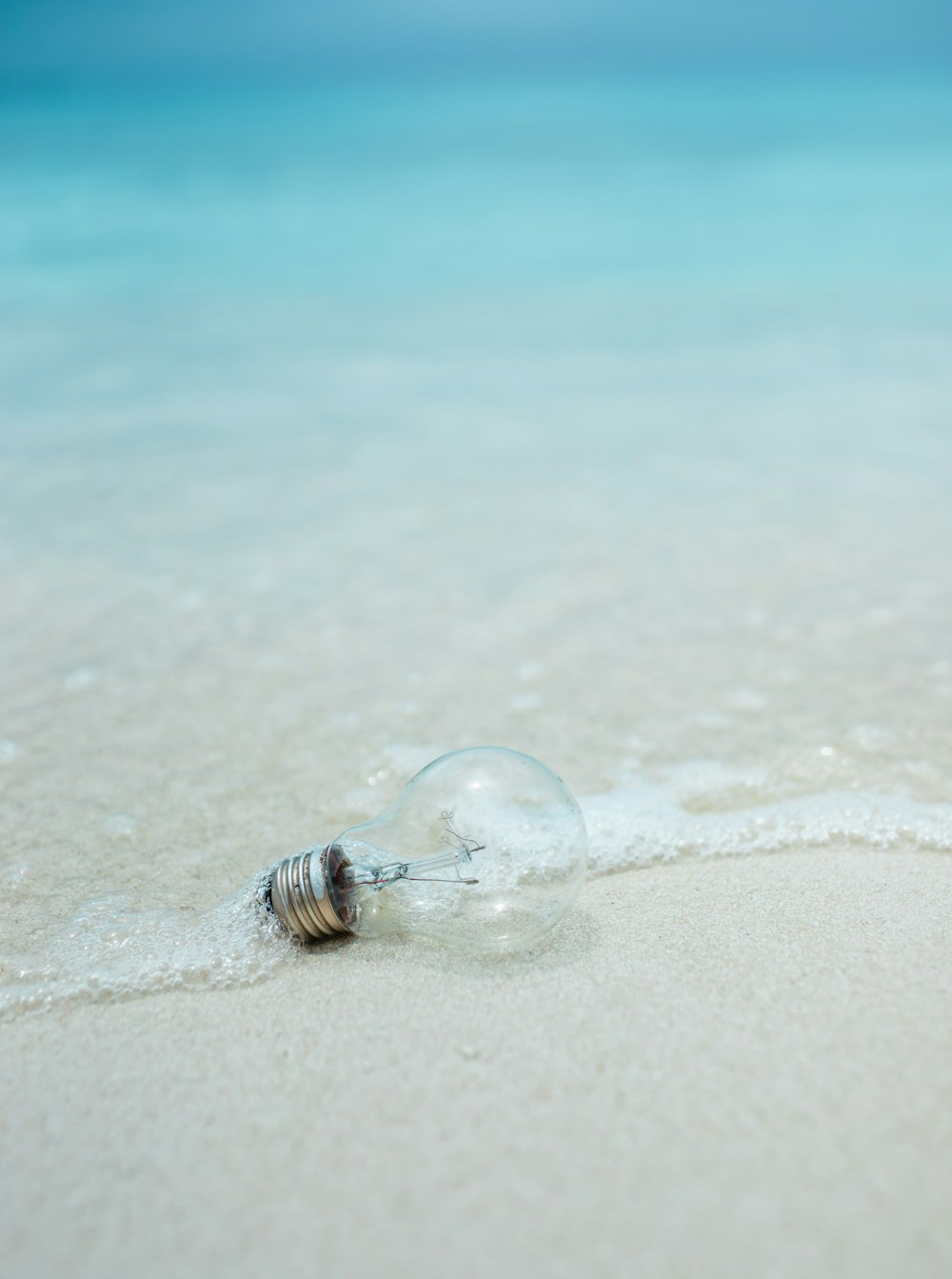 昼間の白い砂浜の上の透明なガラス玉