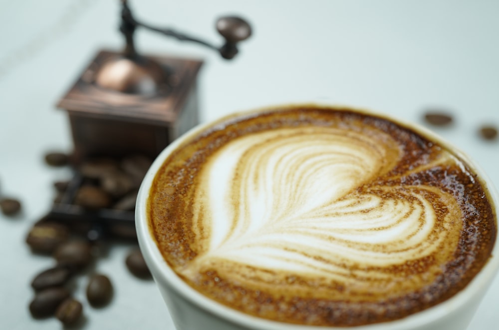 caneca de cerâmica branca com café marrom e branco em forma de coração