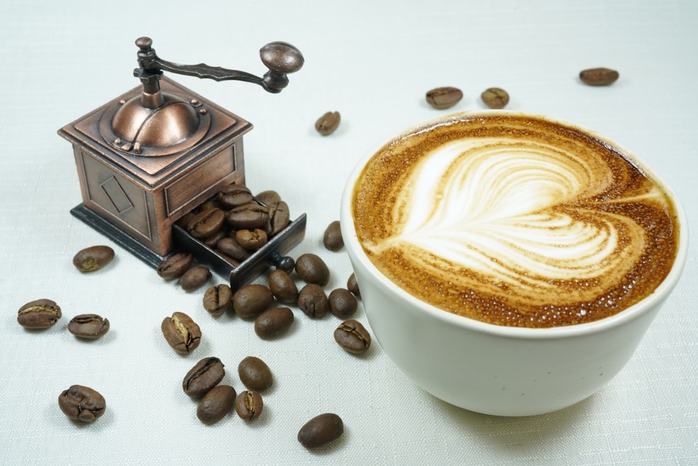 white ceramic cup with coffee beside coffee beans