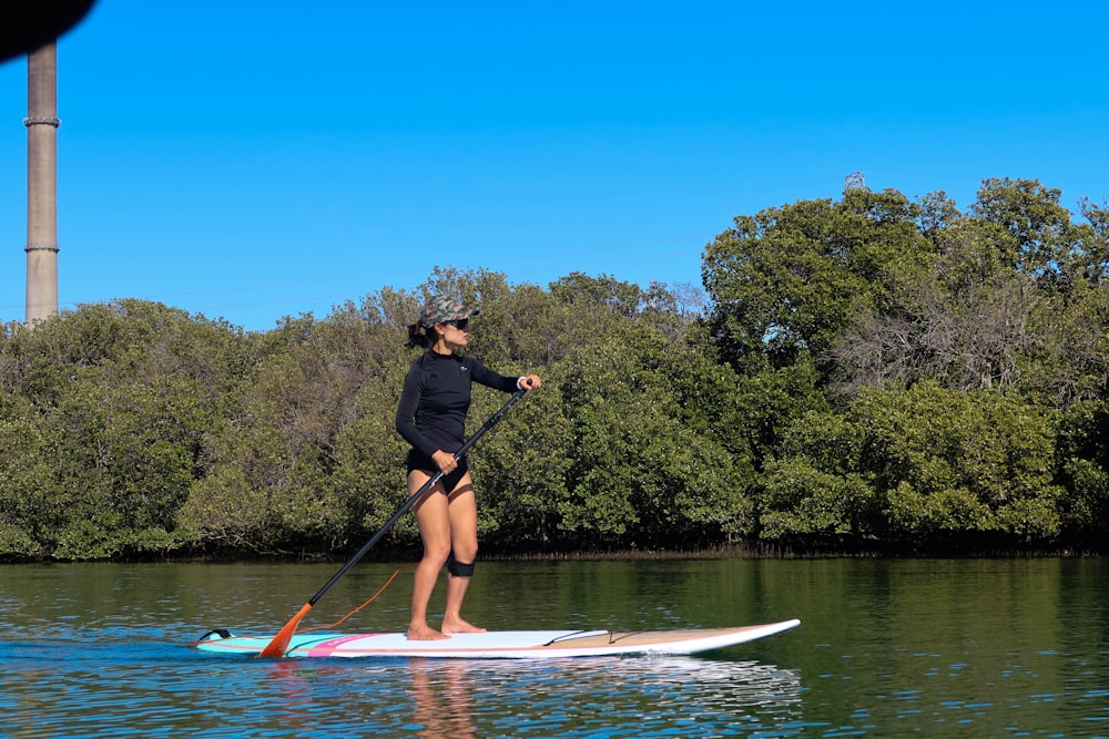 man in black shirt and black shorts riding on white and red surfboard during daytime