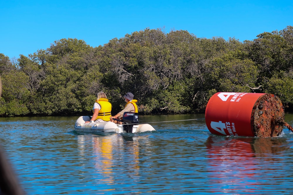 2 personas montando en kayak rojo en el lago durante el día