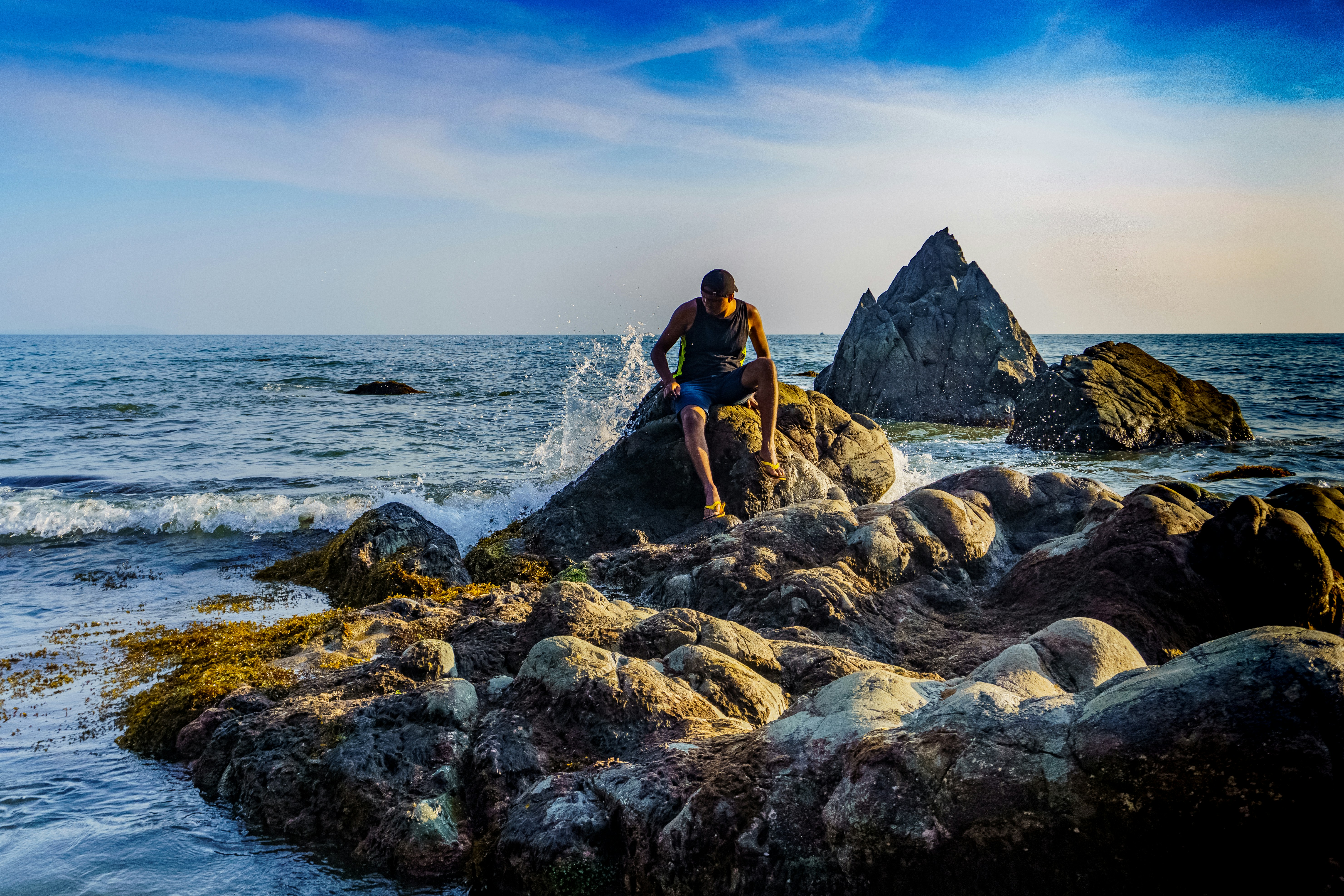 man in black t-shirt and black shorts standing on rocky shore during daytime