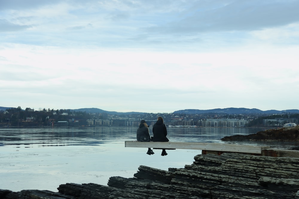 person sitting on rock near body of water during daytime