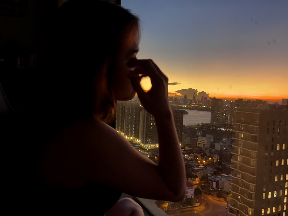 Femme en débardeur blanc tenant un smartphone au coucher du soleil
