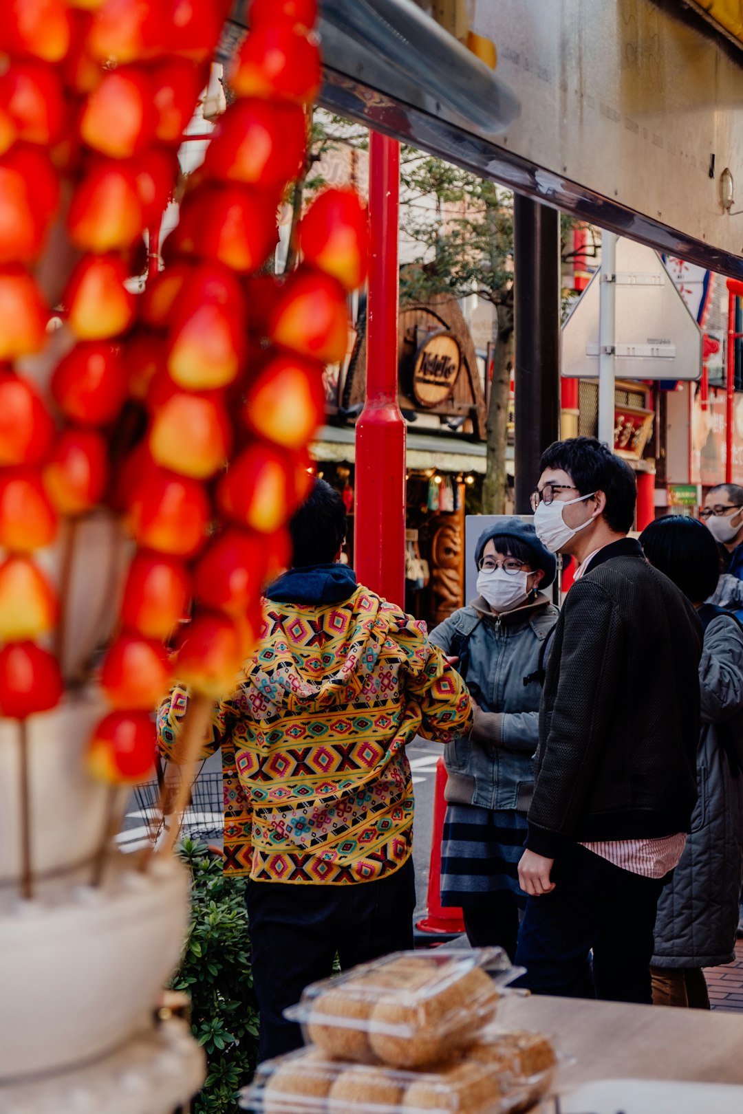 people standing near red round fruits during daytime