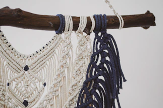 Close-up of delicate macramé knots hanging on a sunlit wall with soft shadows