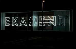 Colorful LED letters spelling out a business name on a busy street.