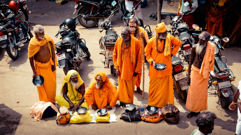 people in orange robe standing on motorcycle during daytime