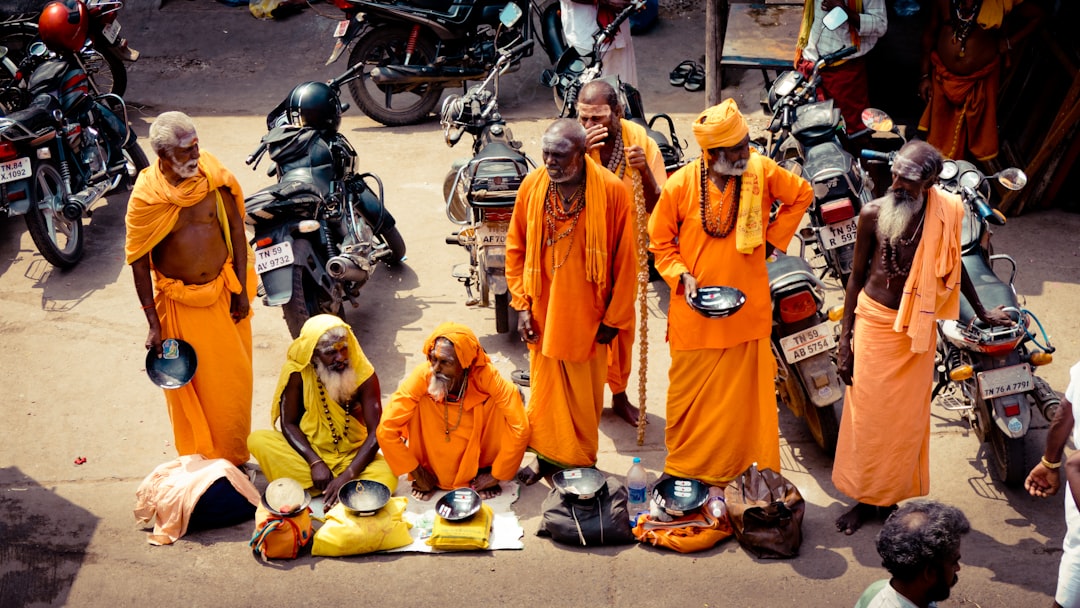 people in orange robe standing on motorcycle during daytime