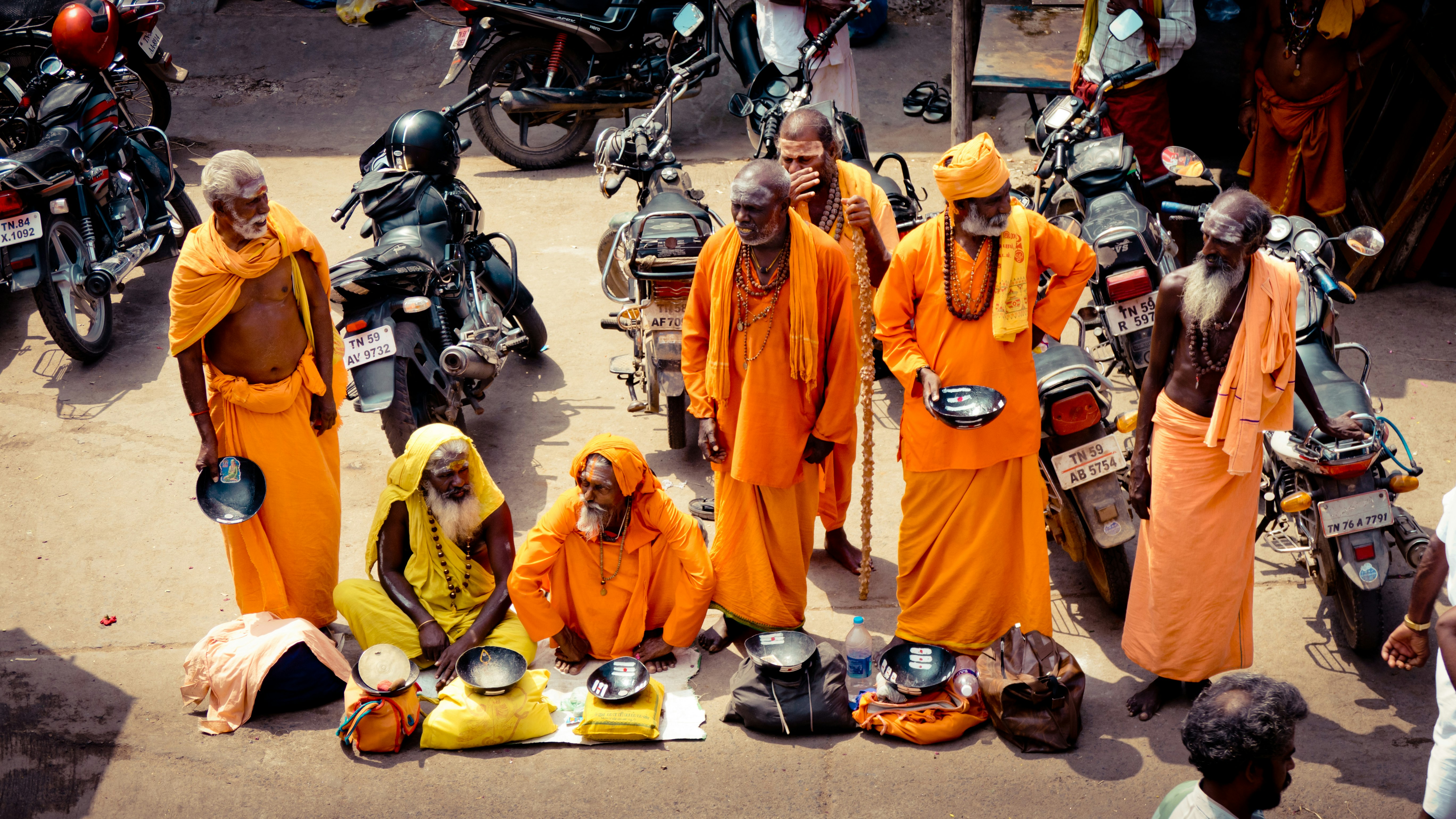 people in orange robe standing on motorcycle during daytime