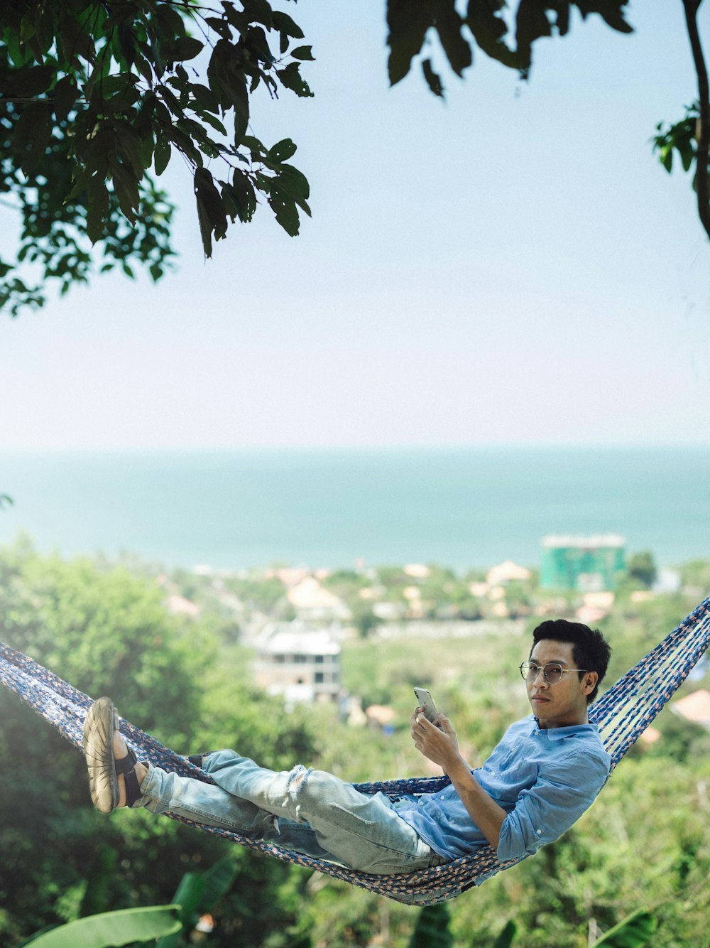 man in blue polo shirt sitting on white metal fence during daytime