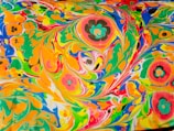 Vibrant and swirling patterns of colors including orange, green, yellow, blue, and red, mixed with floral shapes that create a psychedelic and dynamic visual effect.