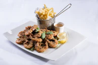 Golden fried shrimp arranged artfully on a plate with fresh lemon wedges.