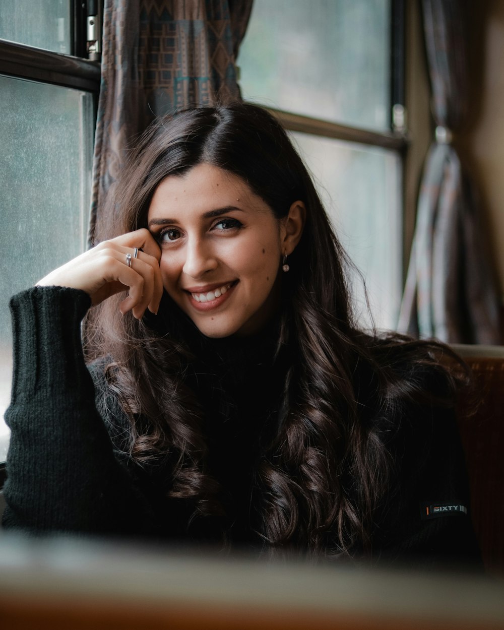 woman in black sweater sitting on brown couch