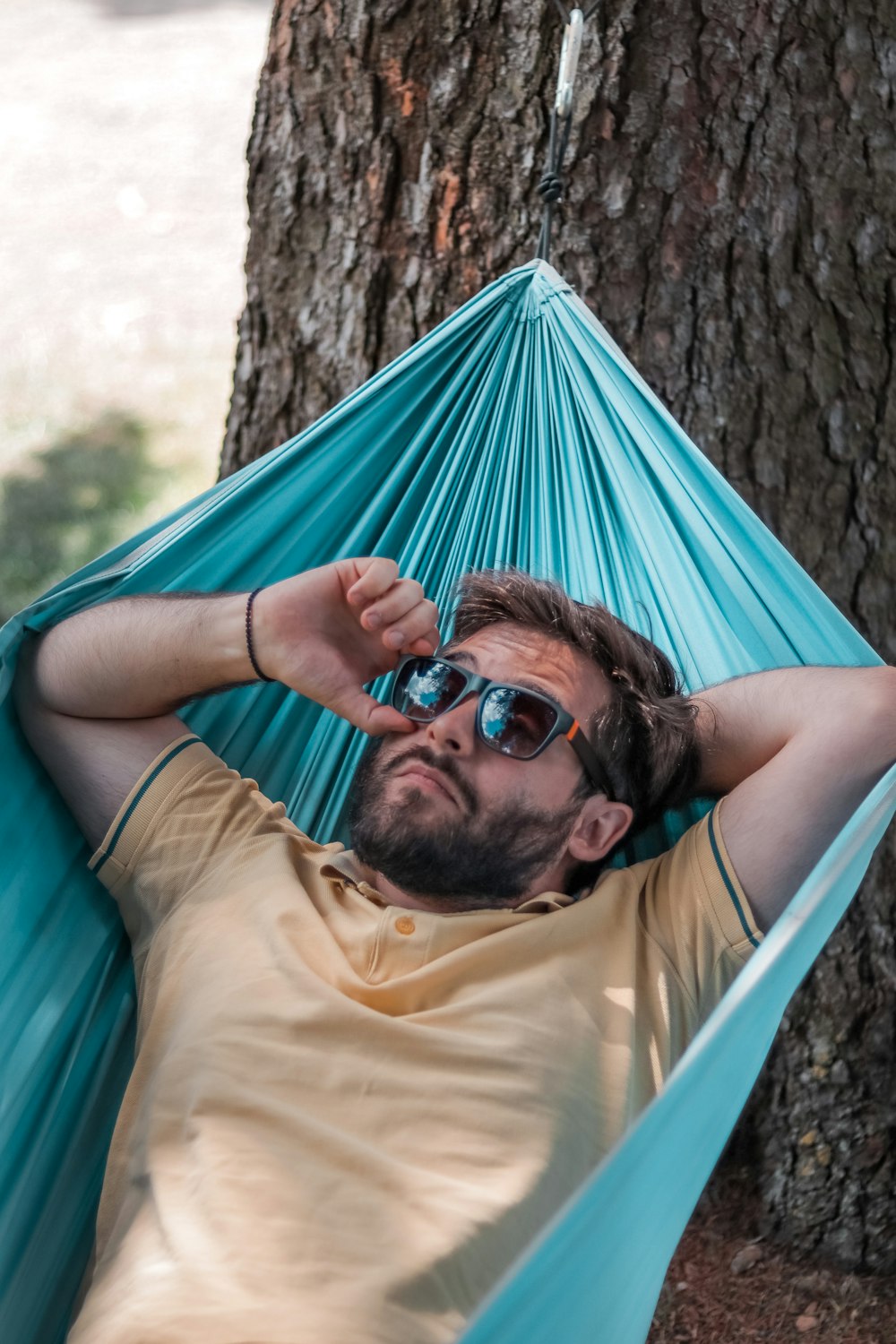 man in yellow crew neck t-shirt lying on blue hammock