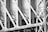 Detailed view of metal girders and beams in an industrial structure. The image showcases numerous rivets and intersecting lines forming geometric patterns. The monochrome tones emphasize the textures and rigidity of the structure.