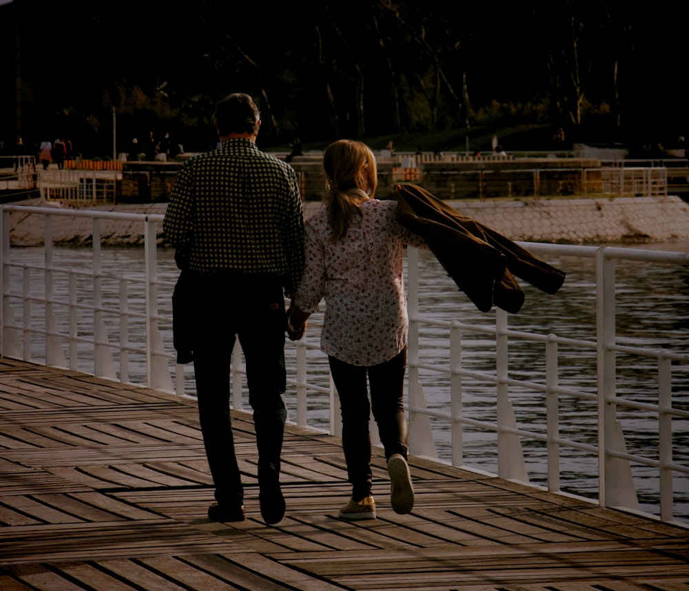 man and woman walking on wooden dock during daytime
