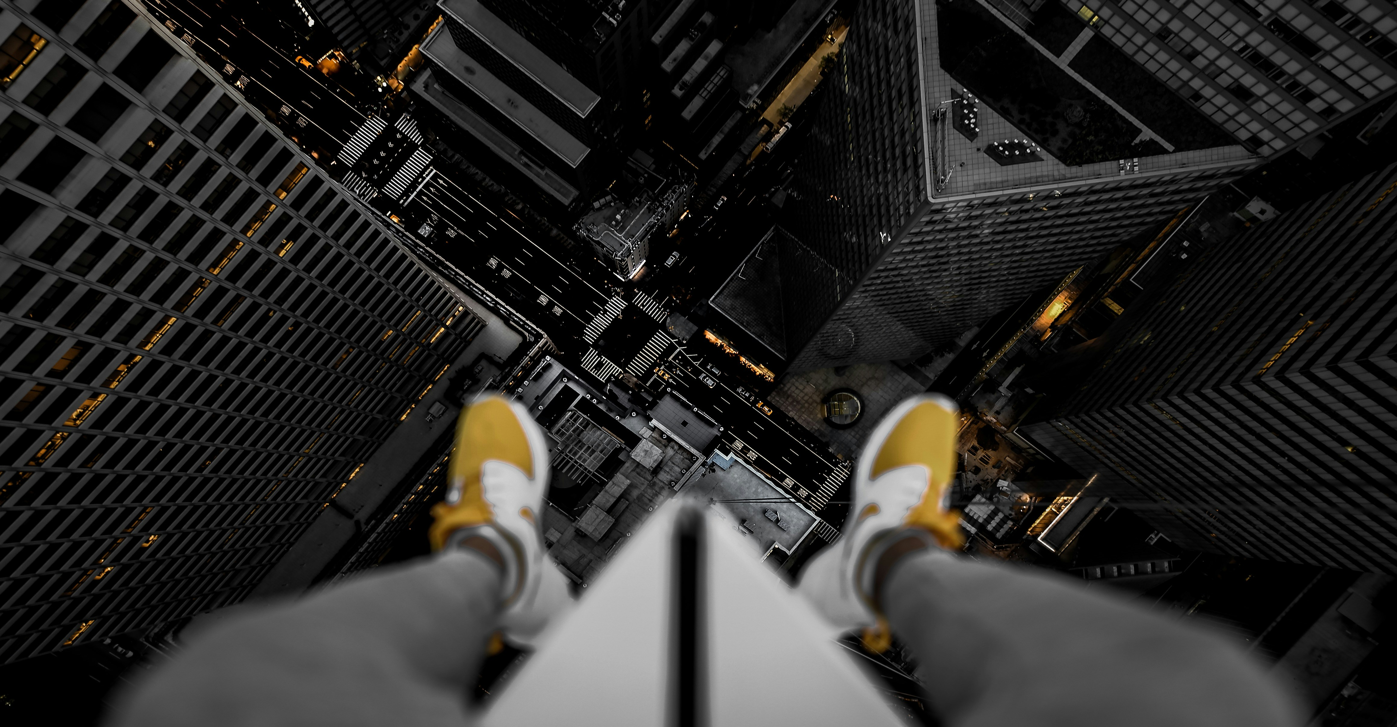 person in black pants and yellow sneakers standing on top of building