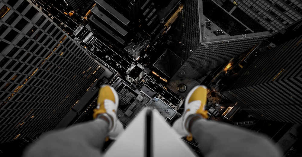 person in black pants and yellow sneakers standing on top of building