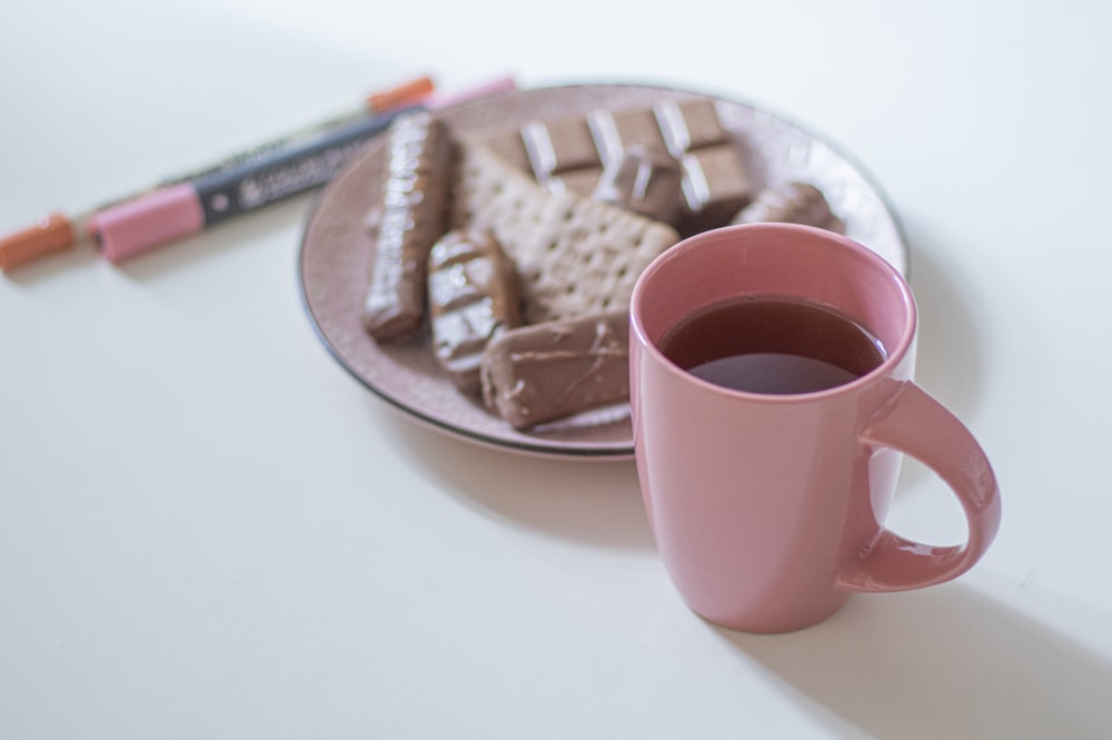 Taza de cerámica rosa en bandeja de madera marrón