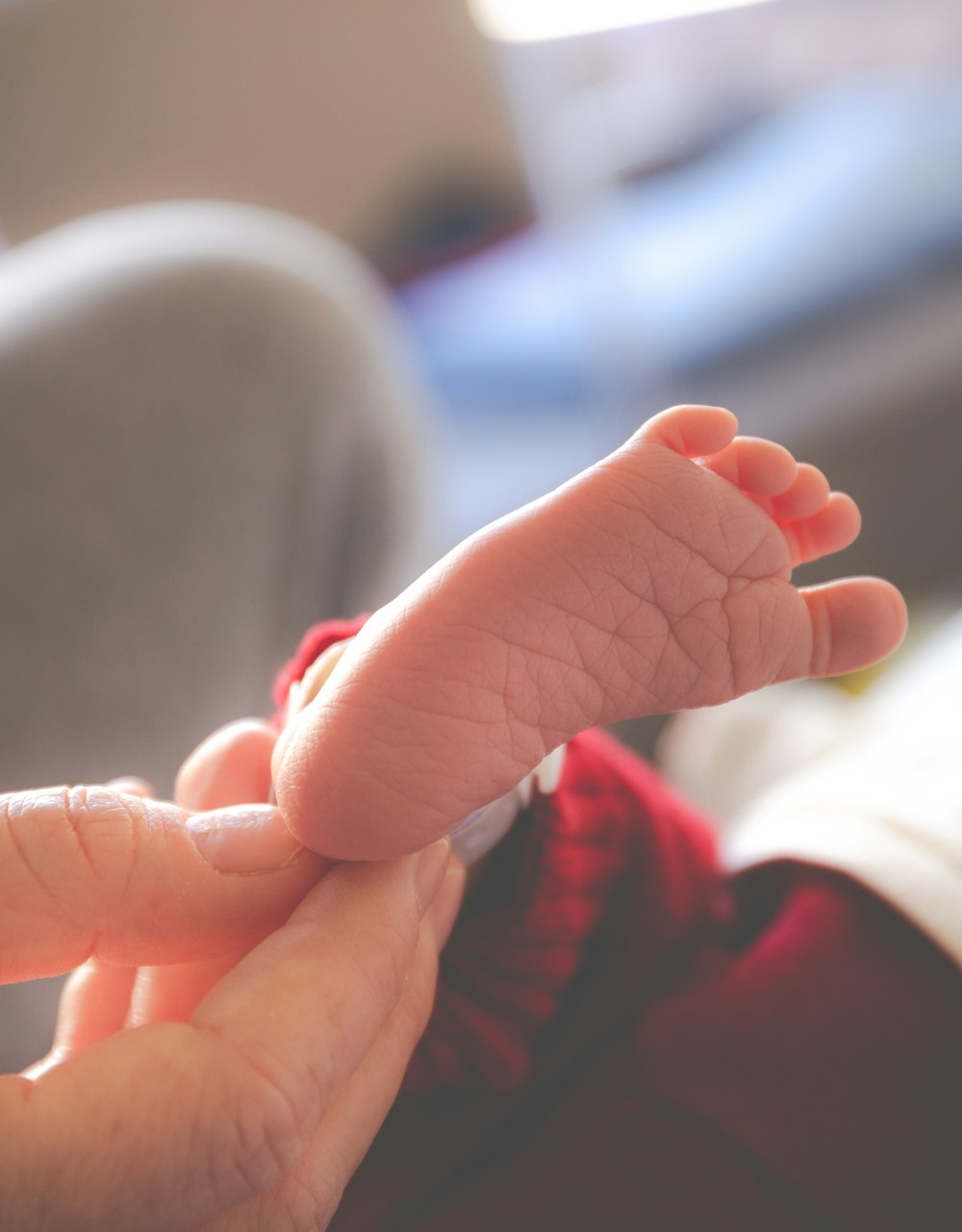 person in red long sleeve shirt holding babys hand