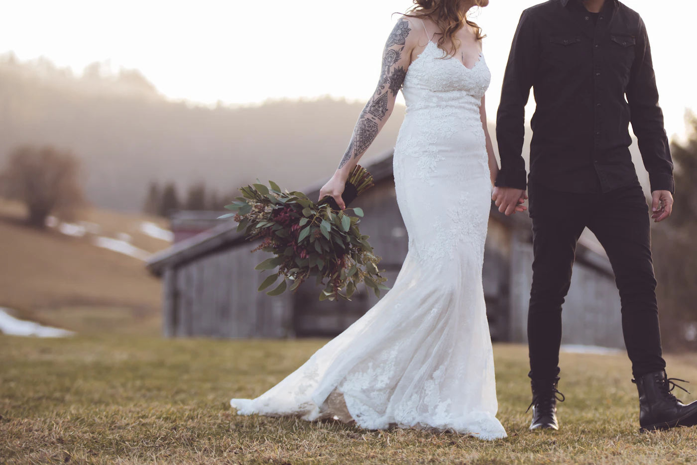 Couple in elopement ceremony attire standing in a dramatic arid landscape with the vast rock formations and the warm desert light creating an otherworldly backdrop
