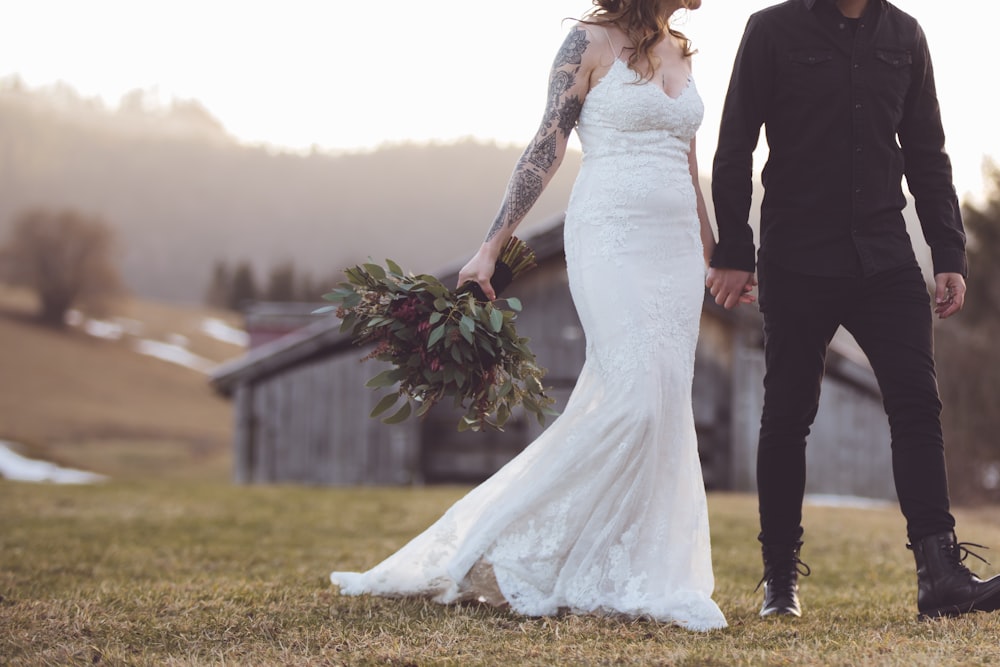woman in white wedding gown standing beside man in black suit