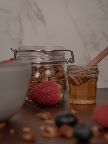 A rustic wooden table displaying jars of Casa Regalado syrup alongside fresh fruit.