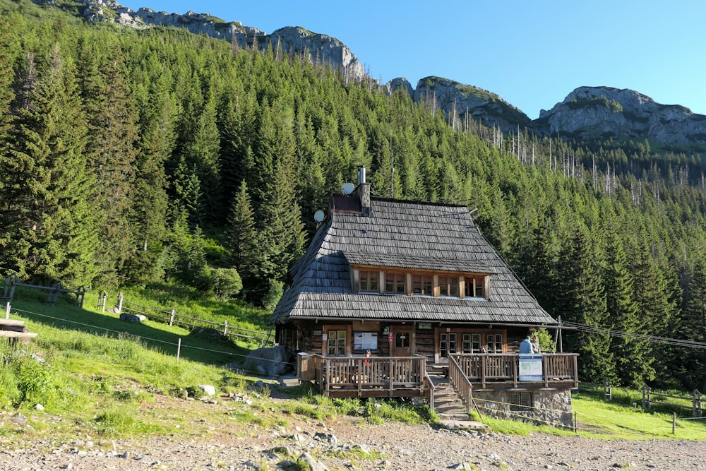 brown wooden house on green grass field near green trees and mountain during daytime