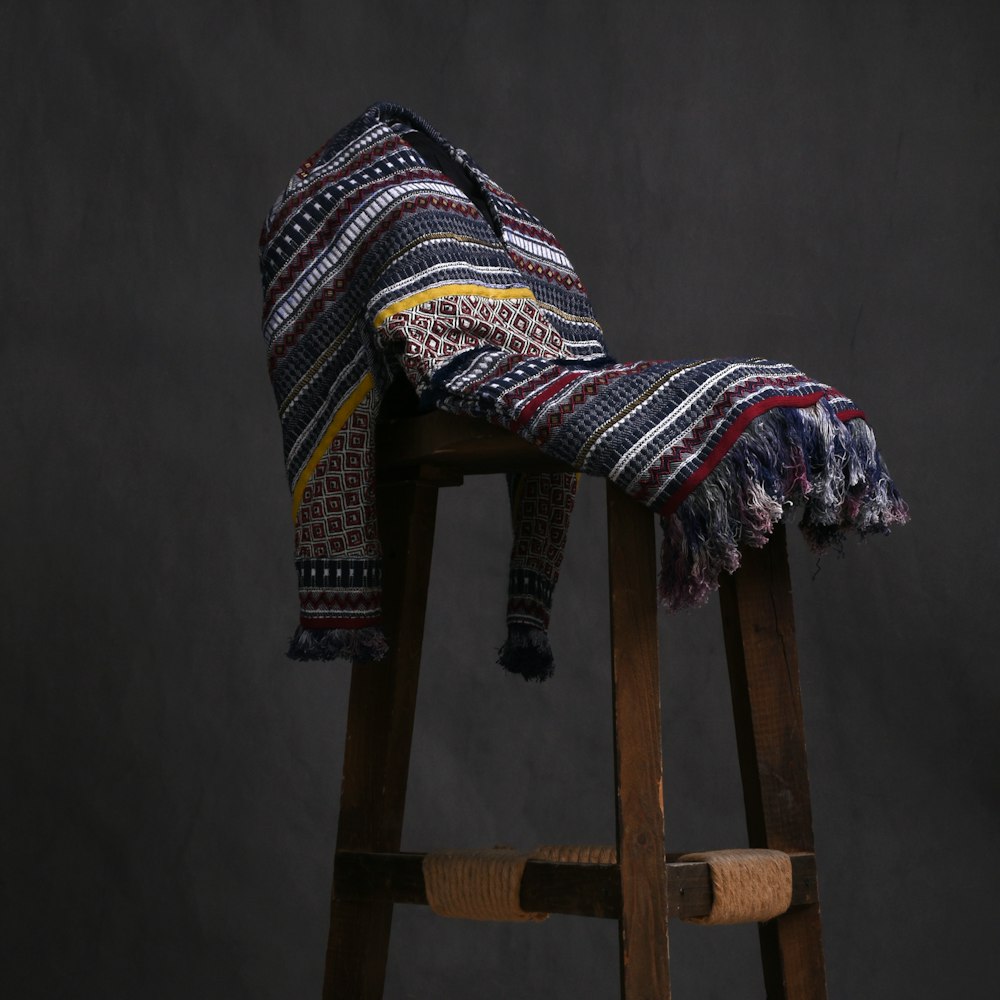 white red and black textile on brown wooden seat