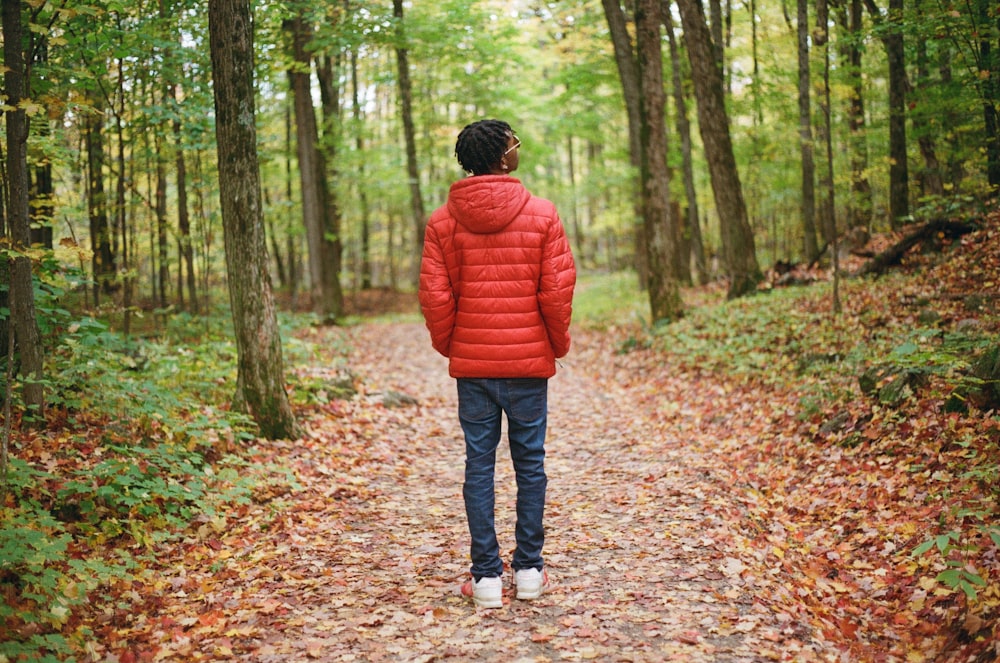 boy in red hoodie standing on dried leaves on ground