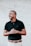 man in black polo shirt standing near white wall