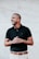 man in black polo shirt standing near white wall