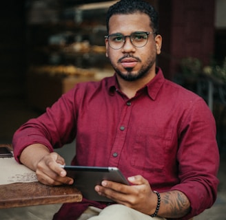 man in red dress shirt holding black tablet computer