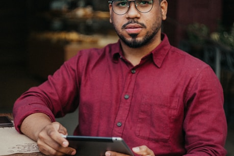 man in red dress shirt holding black tablet computer