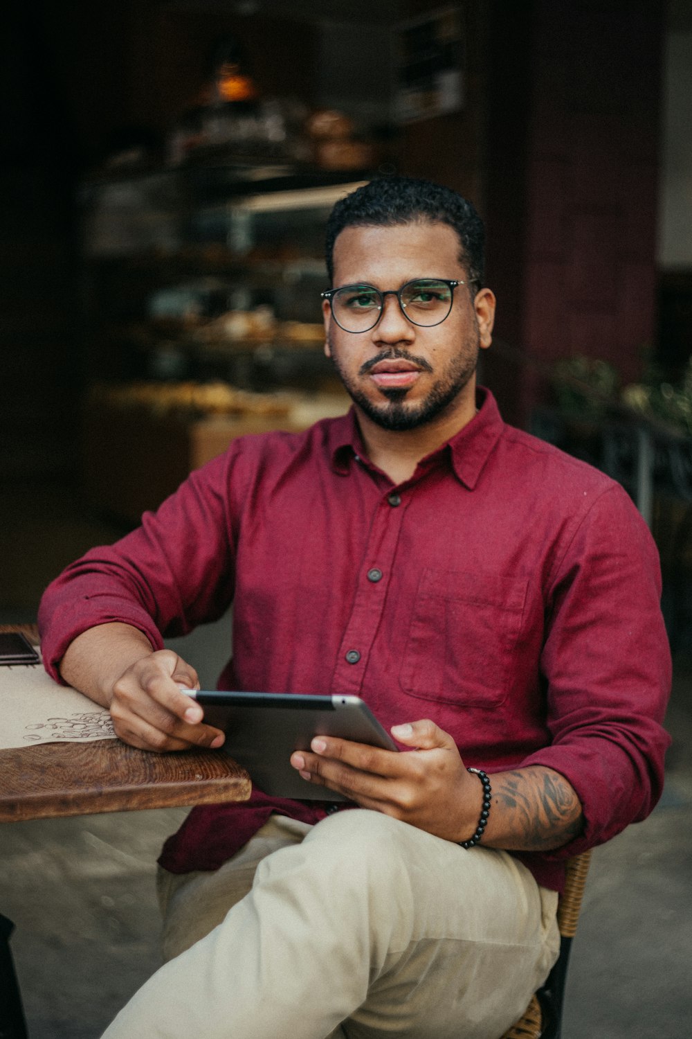 homme en chemise rouge tenant une tablette noire