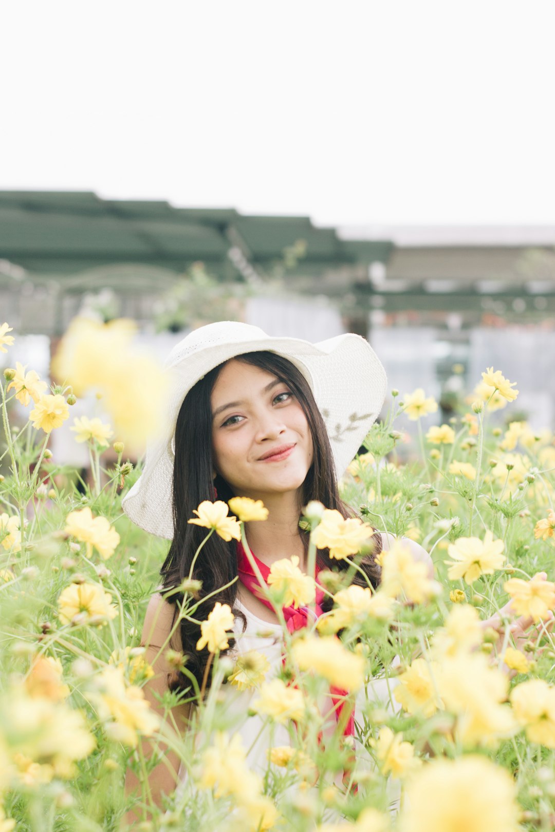 woman in white sun hat holding yellow flowers