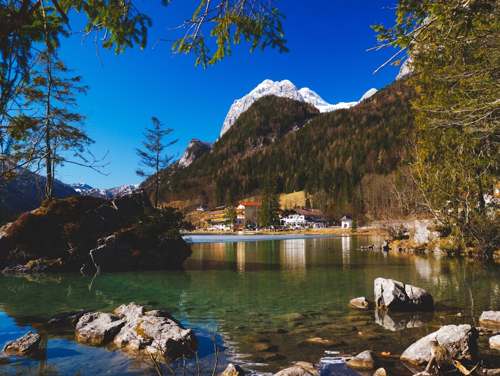 Barca bianca e marrone sull'acqua vicino alla montagna sotto il cielo blu durante il giorno