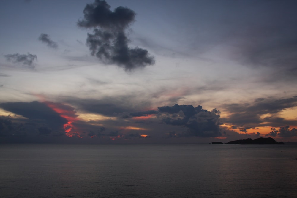 sea under gray clouds during sunset