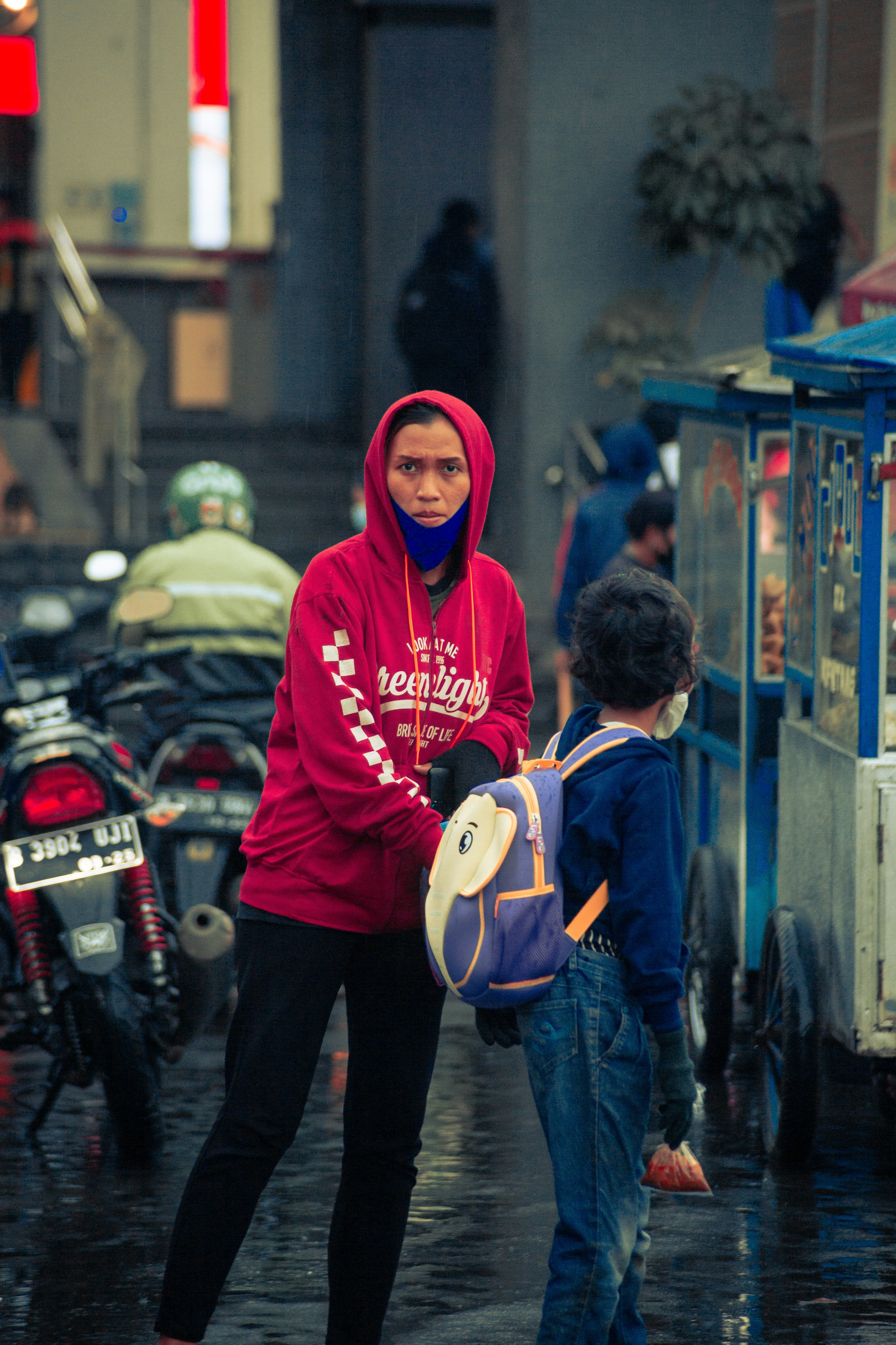 man in red hoodie standing beside boy in blue jacket
