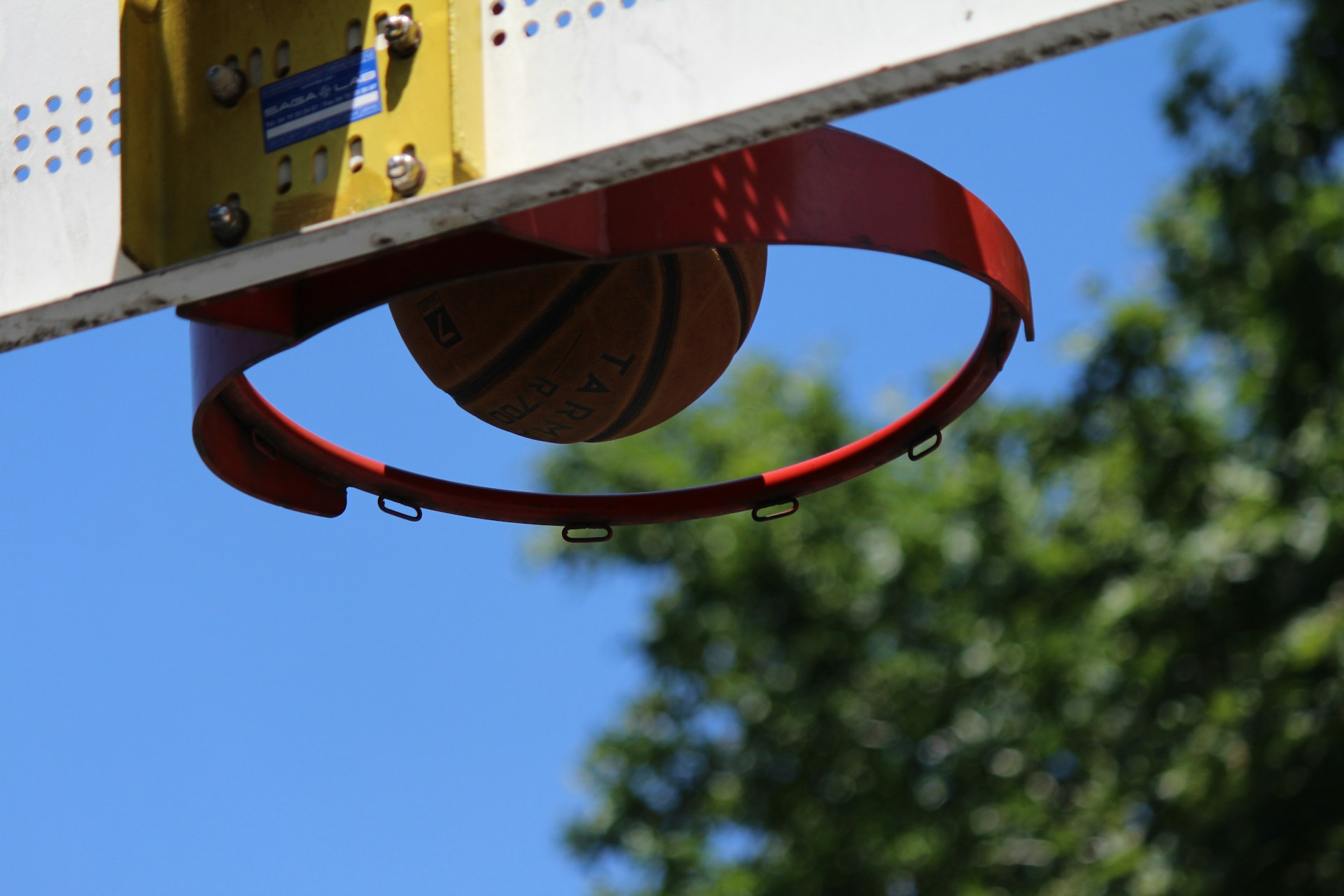 Close-up of a basketball player mid-jump, fingers just about to release the ball towards the hoop.