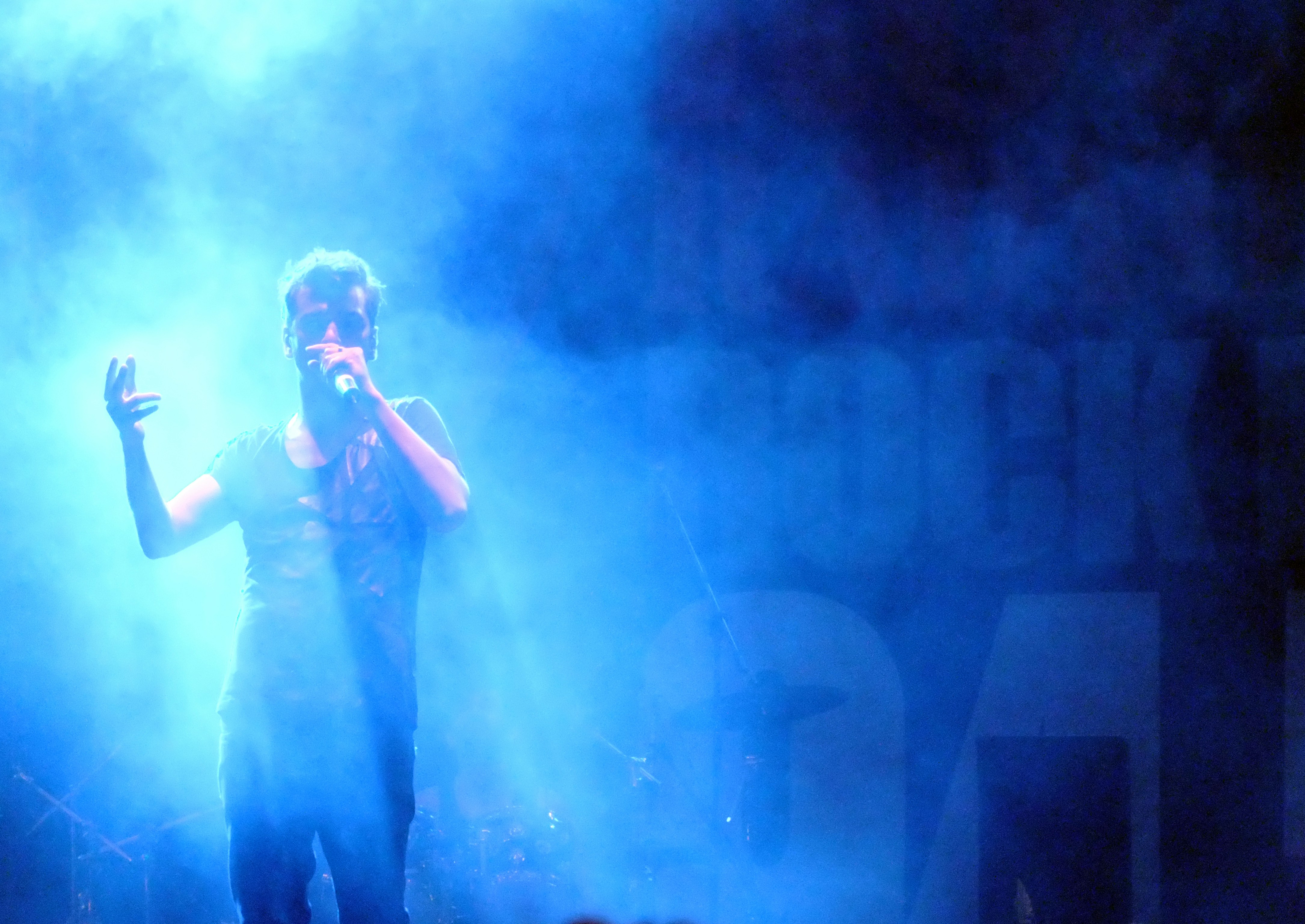 man in black t-shirt singing on stage