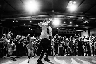 man in white t-shirt and black pants singing on stage
