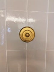 Close-up of a bathroom wall with elegant tile installation and polished fixtures.