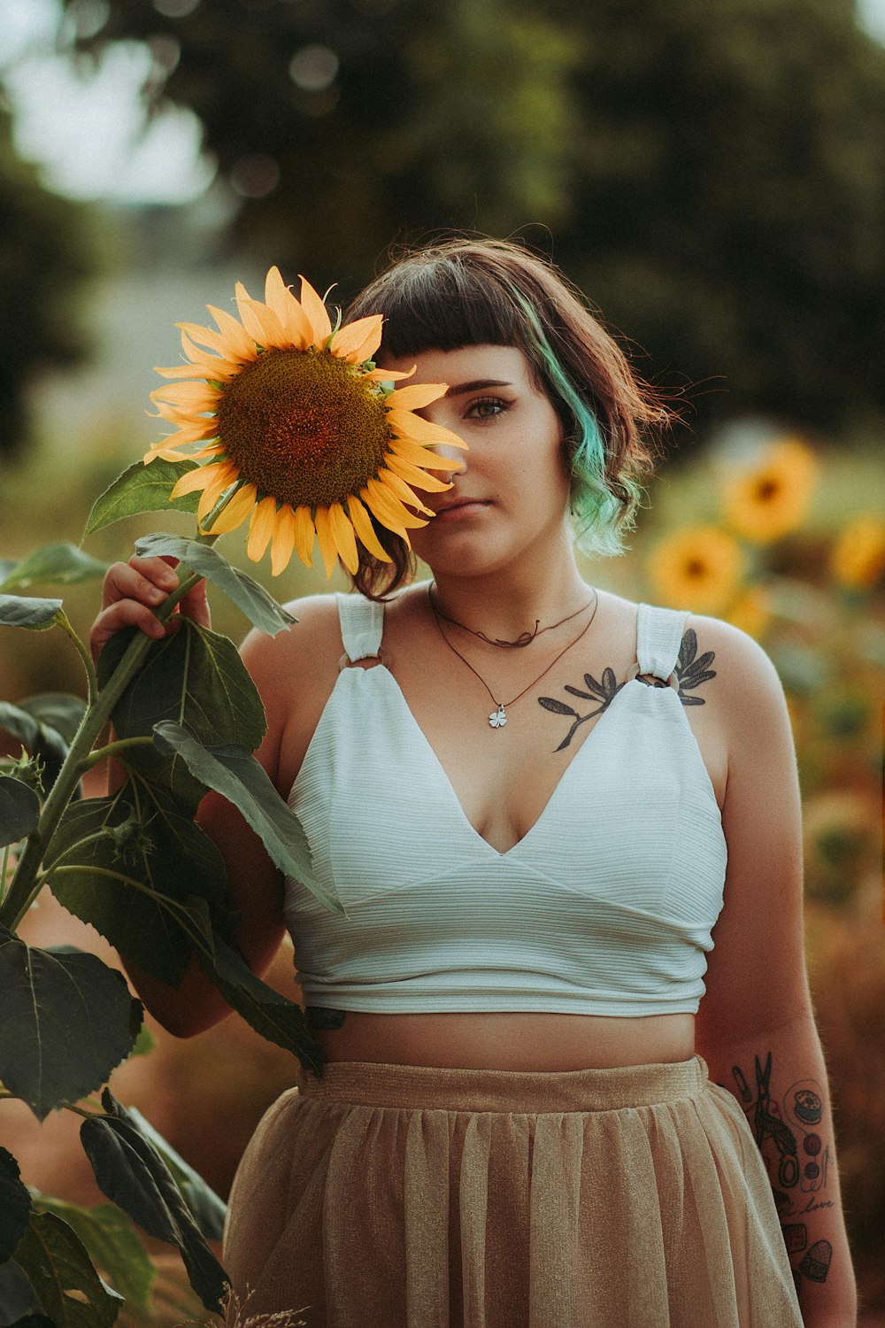 Mujer con camiseta blanca sin mangas sosteniendo girasol