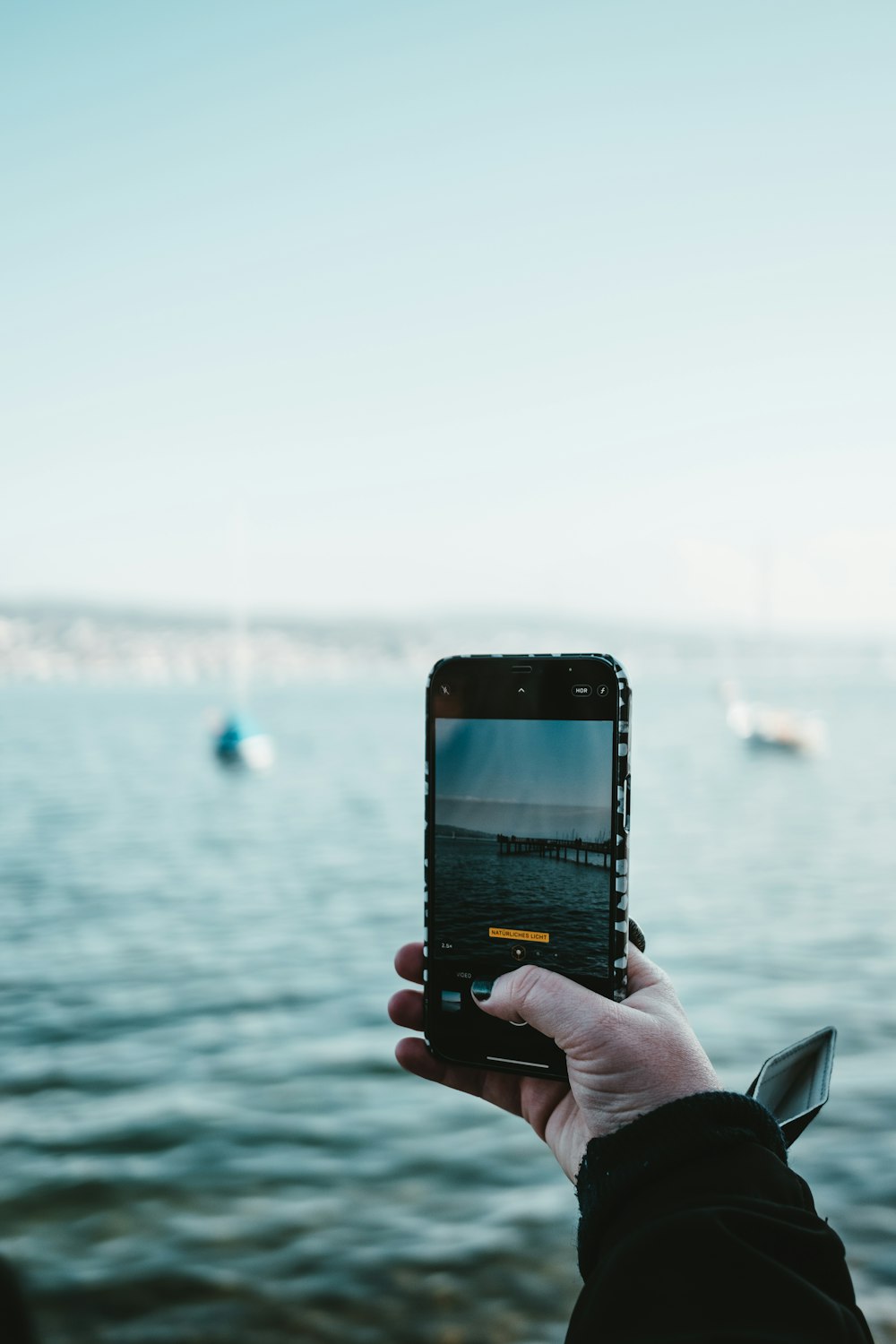 person holding black iphone 5 taking photo of body of water during daytime