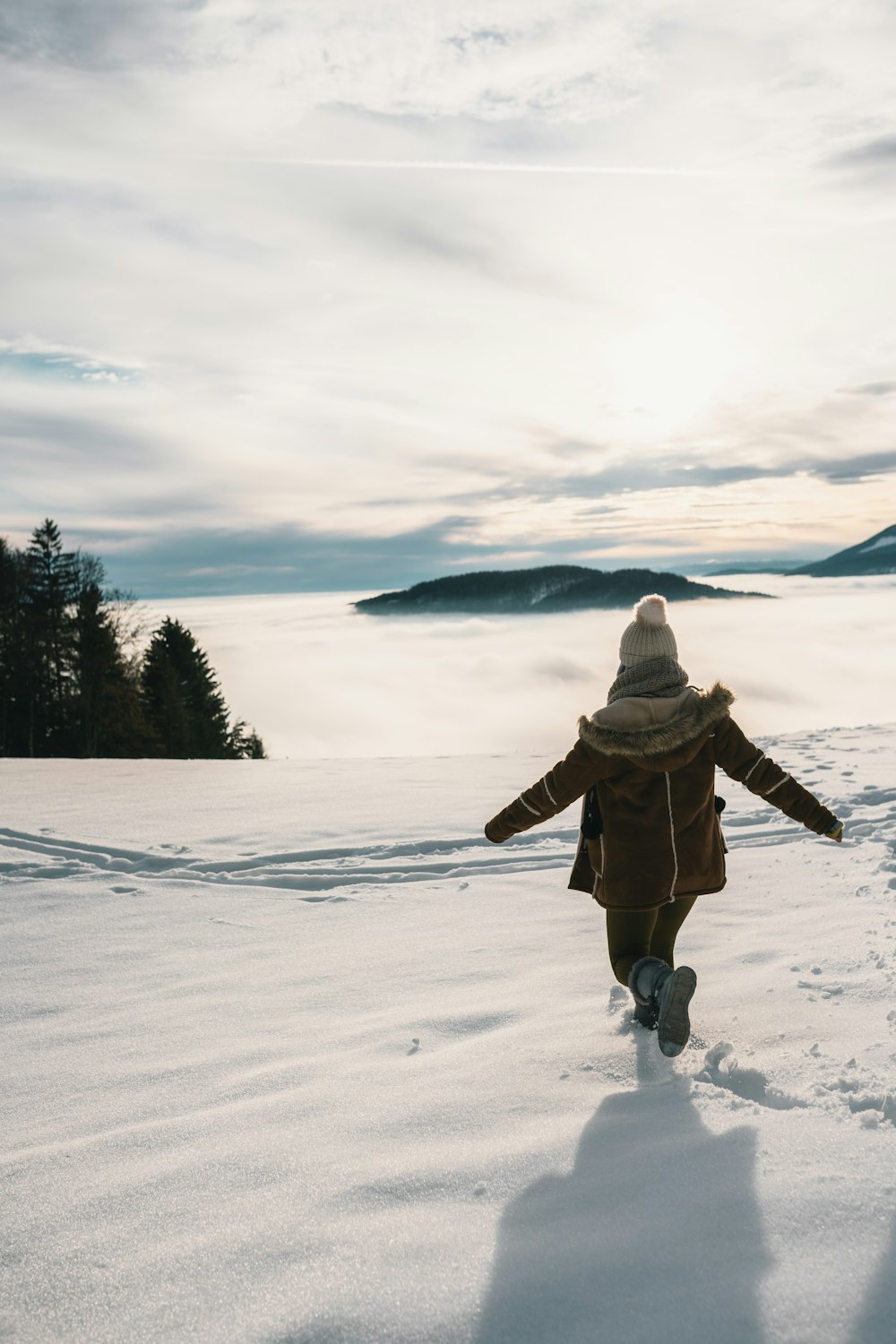 person in brown jacket and brown pants standing on snow covered ground during daytime