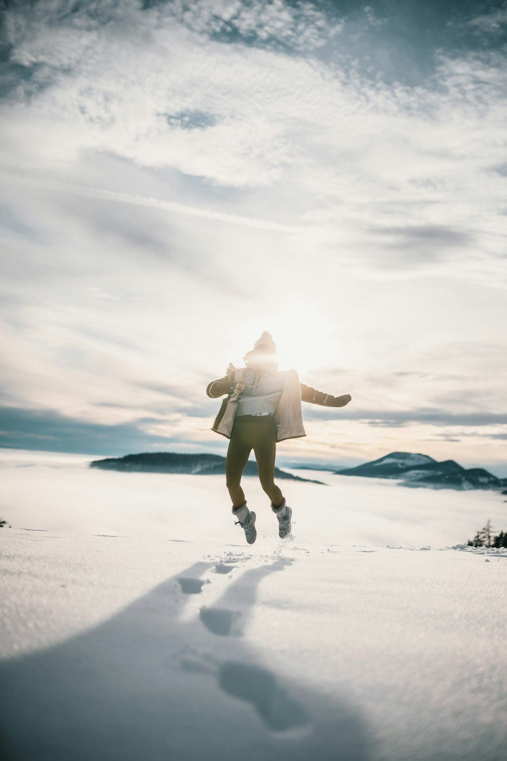 woman in white long sleeve shirt and brown shorts standing on white snow covered field during