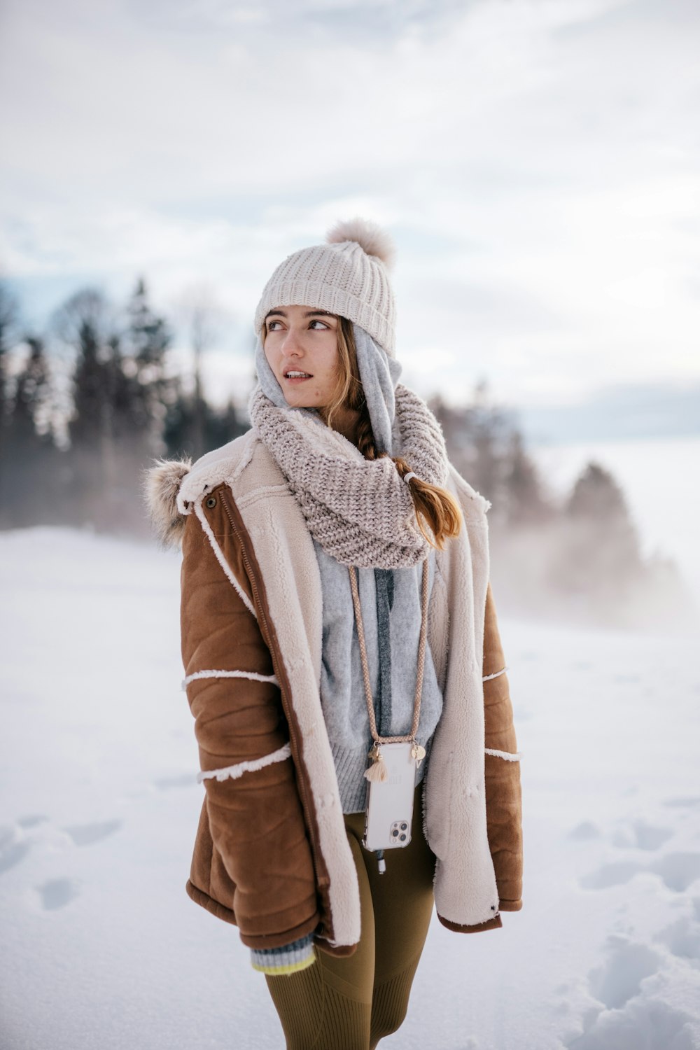 woman in brown coat standing on snow covered ground during daytime