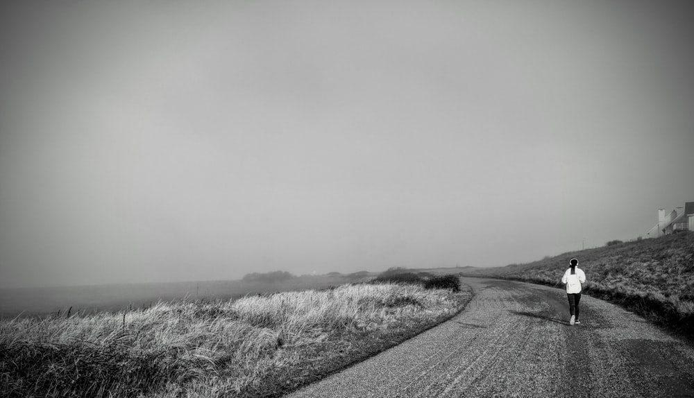 Foto en escala de grises de la carretera en medio del campo de hierba